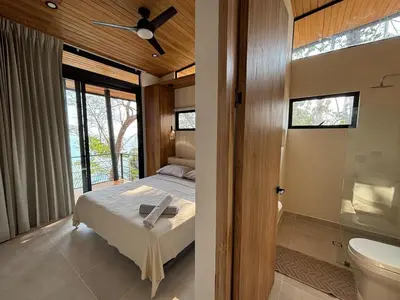 a bedroom with a bed and a bathroom with a toilet at Mar a Cielo Brand New Ocean View Retreat in Mal País