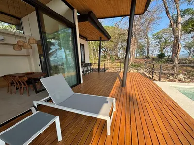 a wooden deck with a chair and a table on a house at Mar a Cielo Brand New Ocean View Retreat in Mal País