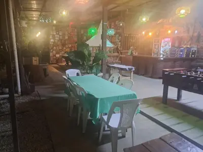 a dining room with a green table and chairs at Sunset House Hostel in Liberia