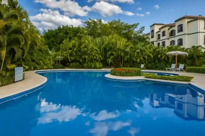 a swimming pool in front of a building with trees at Relaxing 1BR Oasis near Tamarindo in Villarreal