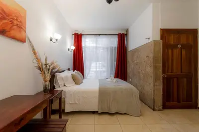 a bedroom with a bed and a window with red curtains at Habitación doble económica - Casa Esmeralda in San José