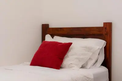 a red pillow sitting on a bed with white pillows at Habitación triple confort - Casa Esmeralda in San José