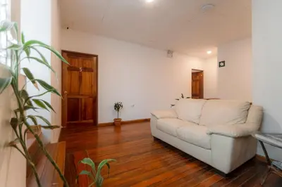 a living room with a white couch and a wooden floor at Habitación doble delux - Casa Esmeralda in San José