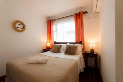 a bedroom with a large bed with an orange curtain at Habitación doble pequeña - Casa Esmeralda in San José