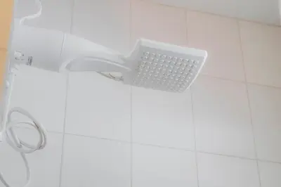 a white shower in a white tiled bathroom at Habitación doble pequeña - Casa Esmeralda in San José