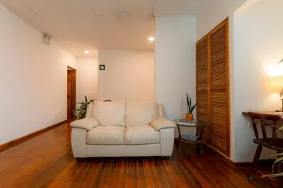 a living room with a white chair and a desk at Habitación doble pequeña - Casa Esmeralda in San José