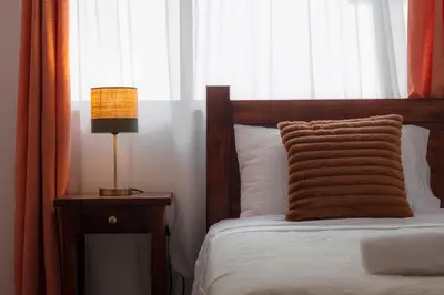 a bed with a pillow and a lamp on a table at Habitacion triple clasica - Casa Esmeralda in San José