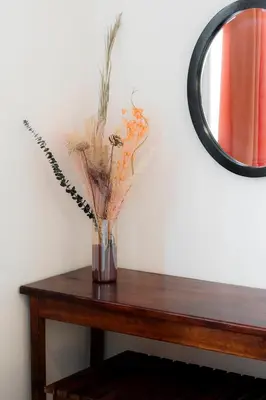 a vase of flowers on a table with a mirror at Habitacion doble delux - Casa Esmeralda in San José