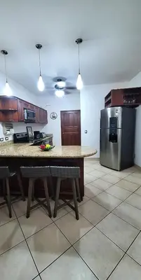 a kitchen with a table and a stainless steel refrigerator at Relajante apartamento cerca de tamarindo in Garita