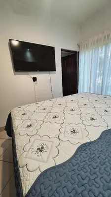 a bedroom with a large bed with a television on the wall at Relajante apartamento cerca de tamarindo in Garita