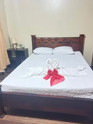 a bed with white sheets and a red bow on it at Doucemaison in Tilarán