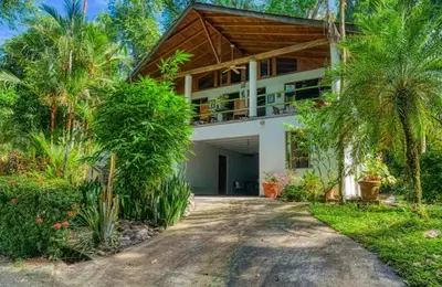 a house with palm trees in front of a driveway at Casa Selva in Dominicalito