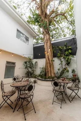 a group of tables and chairs next to a tree at Habitacion familiar - Casa Esmeralda in San José