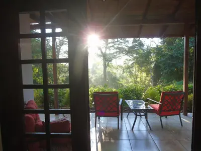 a screened in porch with two chairs and a table at Casas Buenas Brisas in Ojochal