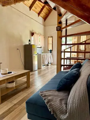 a living room with a blue couch and a kitchen at Cabaña Hojancha in Hojancha