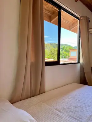 a bedroom with a bed and a large window at Cabaña Hojancha in Hojancha