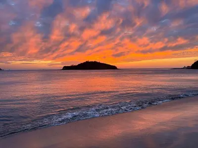 a sunset on the beach with an island in the water at Casa Mathi in Portegolpe