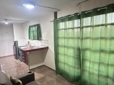 a bathroom with a sink and a green shower curtain at ZuGranjita Alojamiento1 in Alajuela City