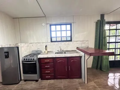 a kitchen with a stove and a sink and a table at ZuGranjita Alojamiento1 in Alajuela City