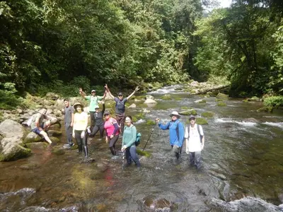 a group of people crossing a stream in a river at Cabaña Tesoro Escondido in Guápiles