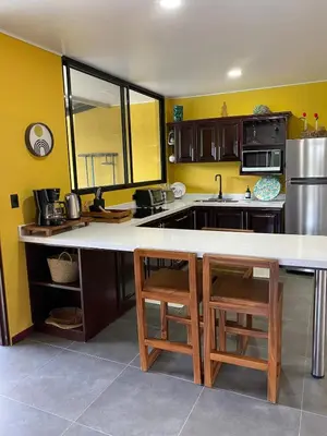 a kitchen with yellow walls and a large white counter at Casa Iriria, in harmony with nature in Carpintero