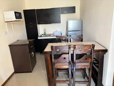 a kitchen with a table and chairs and a refrigerator at Bandera Beach Cabins in Parrita