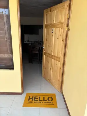 an open door with a welcome mat in front of a house at Bandera Beach Cabins in Parrita