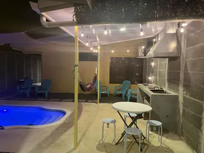 a kitchen and a pool with a table and stools at Bandera Beach Cabins in Parrita