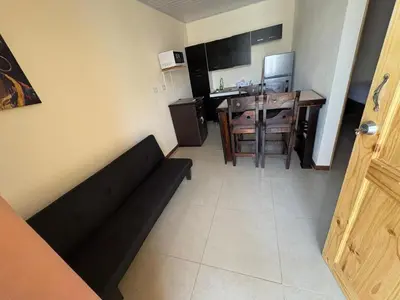 a living room with a black couch and a table at Bandera Beach Cabins in Parrita