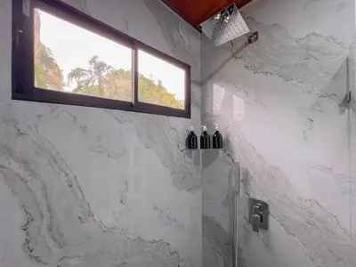 a bathroom with a glass shower with a window at Jalapa's Rural Container Studio in Tilarán