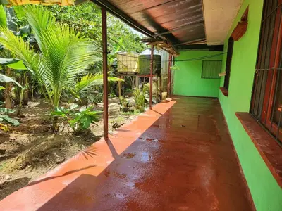 an outside walkway of a house with a green wall at Casa de campo Bijagua in Upala