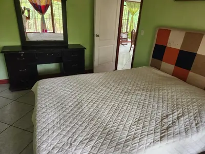 a bedroom with a bed and a dresser and a mirror at Casa de campo Bijagua in Upala