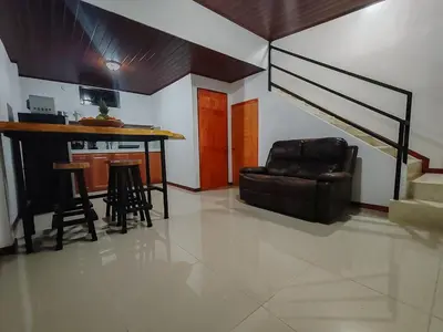 a living room with a couch and a table and stairs at Apartamento Lantanas in Parrita