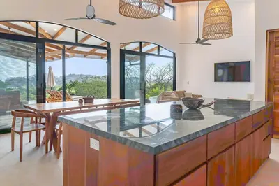 a kitchen with a counter and a dining room with windows at Luxury villa in Samara beach- Casa Armonía in Sámara
