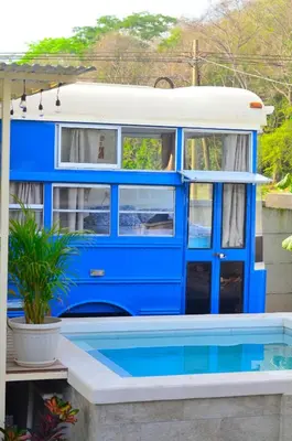 a blue bus parked next to a swimming pool at Bus hotel Playa Barrigona, entre Sàmara y Nosara in Nicoya