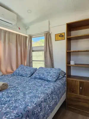 a bedroom with a bed with blue sheets and a window at Bus hotel Playa Barrigona, entre Sàmara y Nosara in Nicoya
