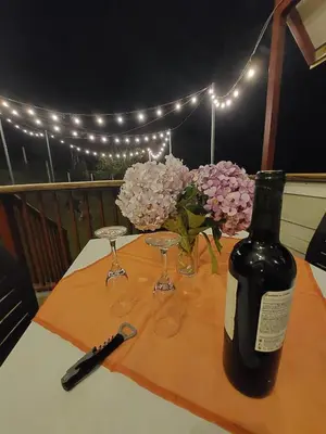 a bottle of wine and glasses on a table with flowers at Chalet IsaKaEla Volcán Turrialba and Views with charming gardens in Turrialba