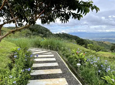 a stone path in a garden with flowers at Safari Tent El Cielo in Santa Ana