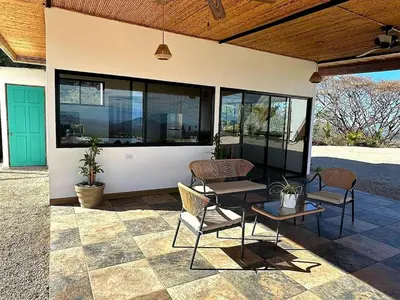 a patio with two chairs and a table and some windows at Blue Sky Lodge in Nicoya