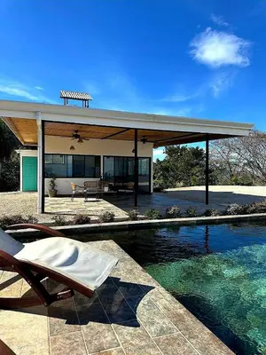 a house with a pool in front of it at Blue Sky Lodge in Nicoya