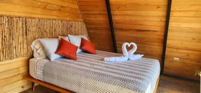 a bed with two pillows and a swan on it at Blue Sky Lodge in Nicoya