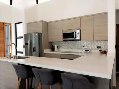 a kitchen with a large white counter with chairs at Casa Mobula - Modern single-level Home, private Pool, near Beach in Potrero