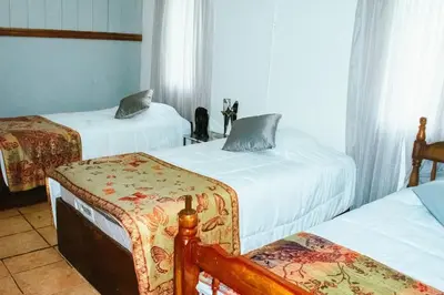a room with two beds and a chair in it at Casa Posada Margarita in Bijagua