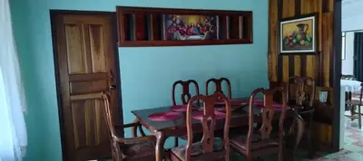 a dining room with a wooden table and chairs at Casa Posada Margarita in Bijagua
