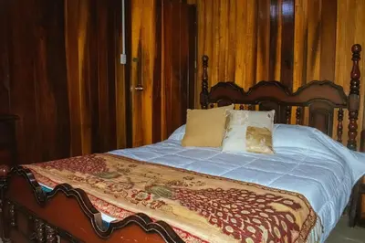 a bed with a wooden headboard and pillows on it at Casa Posada Margarita in Bijagua
