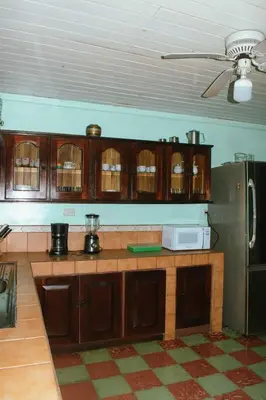 a kitchen with wooden cabinets and a refrigerator at Casa Posada Margarita in Bijagua