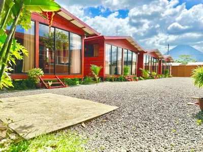 a red house with glass windows on a gravel driveway at Tribu Bungalows Romantic & Confortable 2 in Fortuna