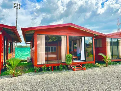 a red house with a bench in front of the water at Tribu Bungalows 3 Romantic Spot in Fortuna