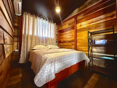 a bedroom with a bed and a wooden wall at Tribu Bungalow 4 Centrally located and comfortable in Fortuna