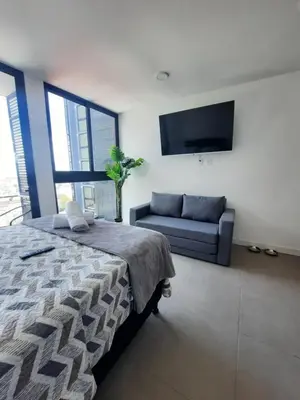 a bedroom with a bed and a couch and a flat screen tv at Nuevo y moderno loft en Bö Escalante in San José